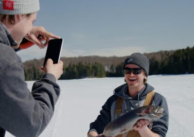 person taking picture of the fish that was caught while ice fishing